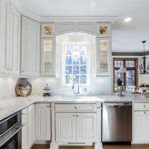 White kitchen sink area with best kitchen cabinet materials, crown molding and marble countertops
