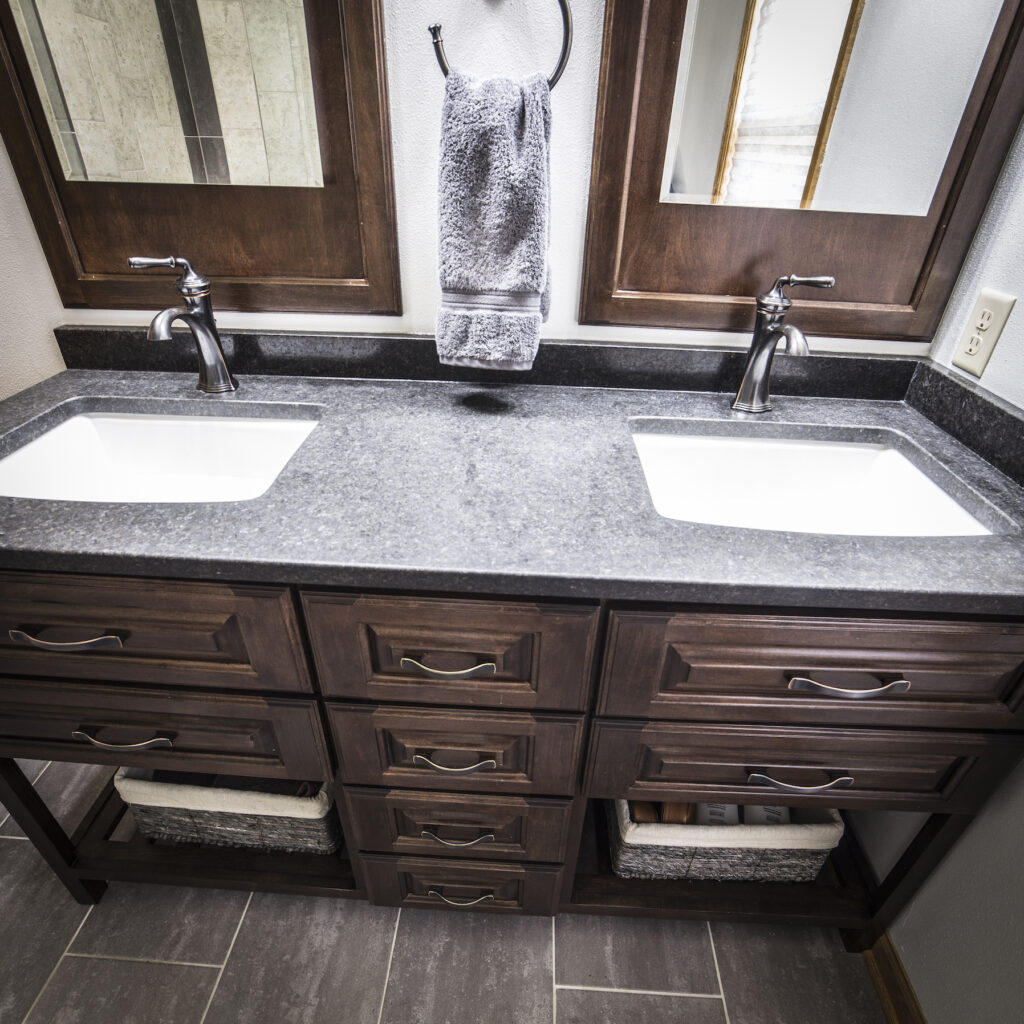 Pewter grey granite countertop with dual sinks and dark brown vanity for bathroom remodel.