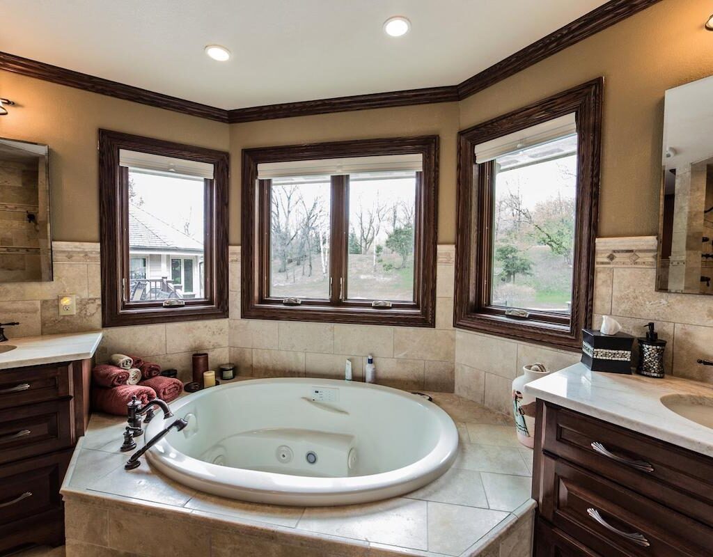 Tile jetted tub surround with bronze faucet and lots of natural light.