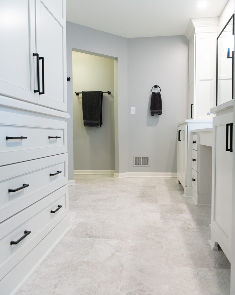 White bathroom cabinets and countertop with light colored floor tiles