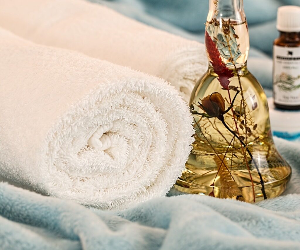 Plush bathroom towels next to massage oil